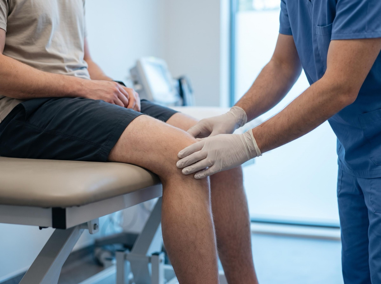 A clinician examining a patient's knee.